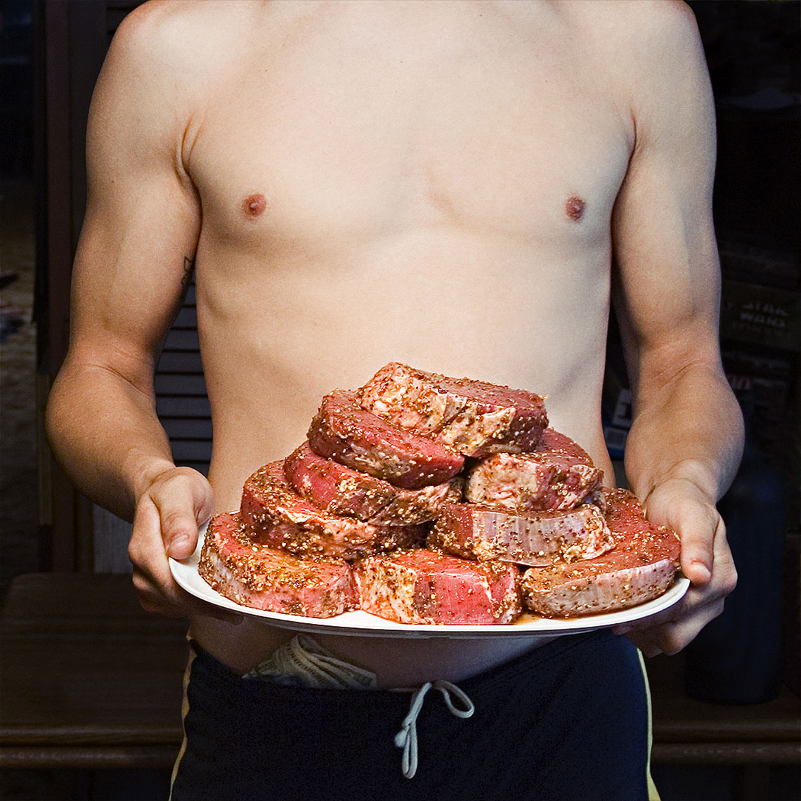 Meat on the plate held by a shirtless guy